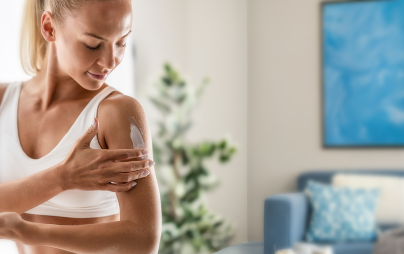 Vrouw die spiergel smeert op bovenarm 