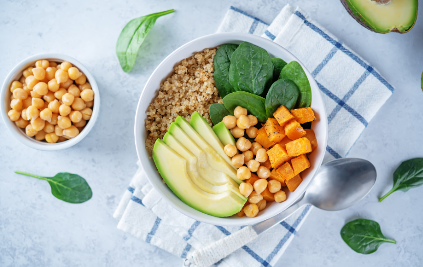 Een buddha bowl met avocado, rijst, zoete aardappel, spinazie en kikkererwten.