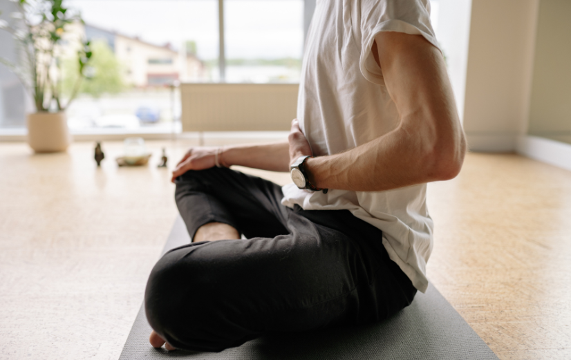 Man zit op de grond en doet meditatie oefeningen om zijn darmen tot rust te brengen.
