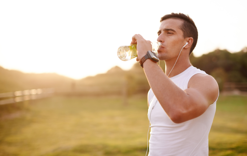 Man neemt pauze van hardlopen en drinkt water met elektrolyten als aanvulling op zijn sportroutine.