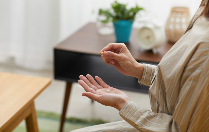Vrouw met supplementen in haar hand die ze makkelijk inneemt met deze tips.