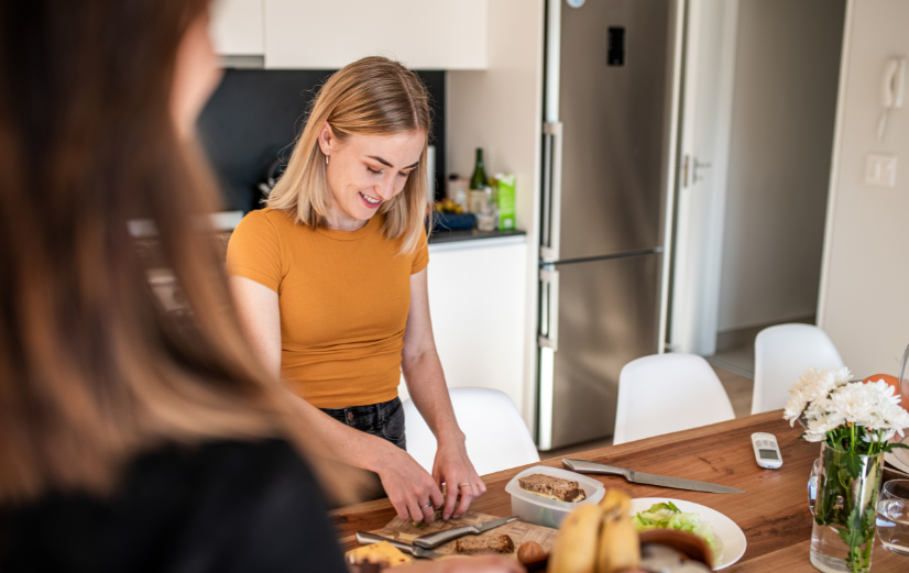Vrouw staat in de keuken en maakt zelf een gezond ontbijt om weer terug in het ritme te komen na de vakantie.
