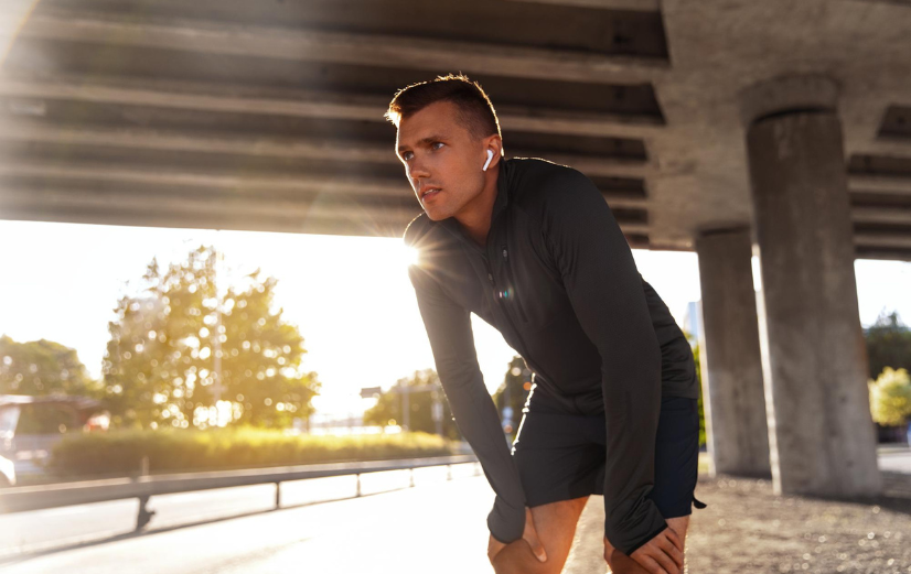 Man in sportkleding neemt rust tijdens het hardlopen en denkt aan het belang van vitamine B12 aanvullen.
