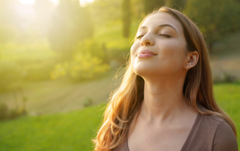 Vrouw staat met gezicht in de zon om vitamine D op te bouwen.